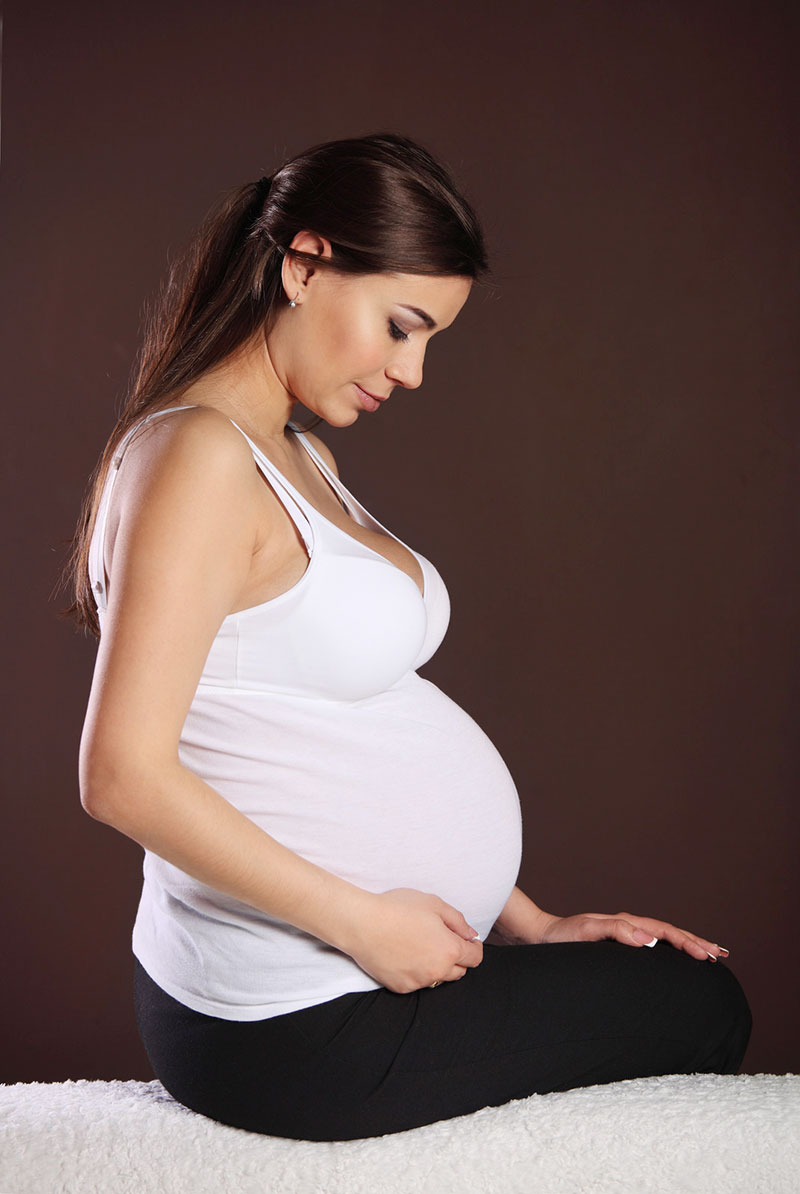 Pregnant women sitting on massage table.